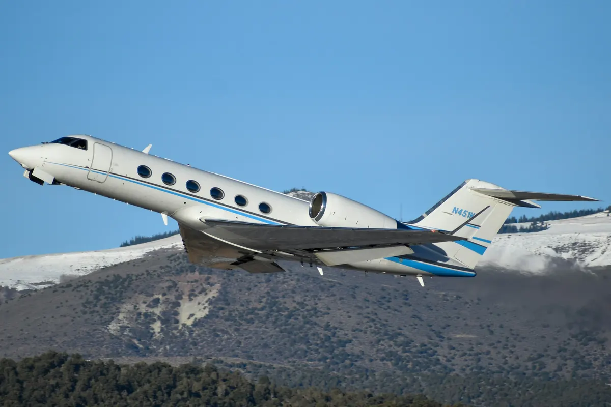 Large business jet climbing over snow-covered mountains