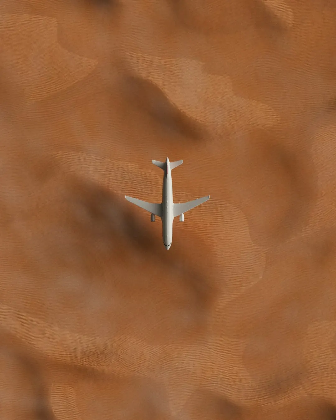 An aircraft crossing desert dunes, seen from above
